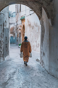 Rear view of woman walking on street amidst buildings