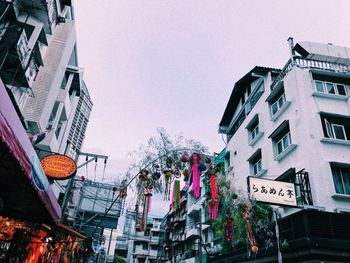 Low angle view of lanterns hanging by buildings against sky
