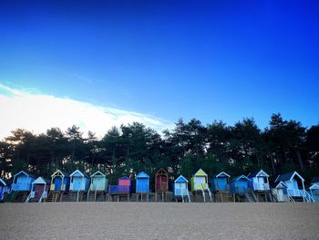 Row of chairs at beach against blue sky