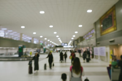 Defocused image of people walking on illuminated ceiling