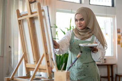 Portrait of young woman standing by railing