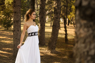 Woman standing by tree trunk