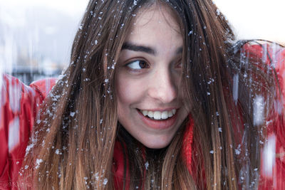 Portrait of a smiling young woman with snow in her hair