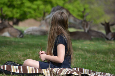 Rear view of woman sitting on field