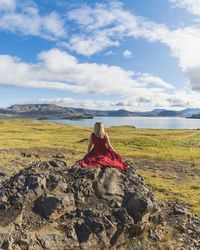 Woman sitting on field against sky