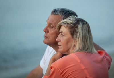 Thoughtful mature couple looking away against sky