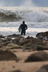 Rear view of man on rock at beach