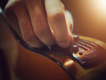 Close-up of person hand adjusting control in guitar