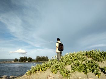 Rear view of woman standing on rock against sky