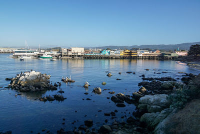 The colorful buildings on the wharf reflect off the still bay waters.