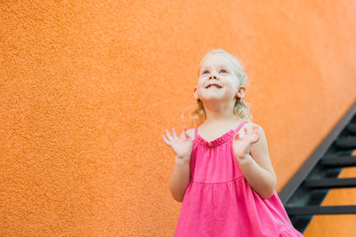 Young woman standing against yellow wall