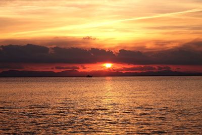 Scenic view of sea against dramatic sky during sunset