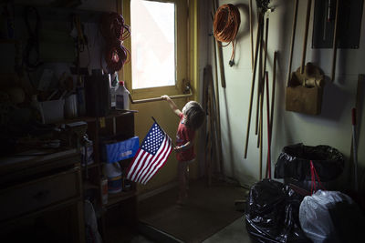 Boy holding american flag, looking through window