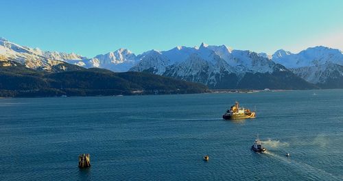 Scenic view of sea and snowcapped mountains against sky