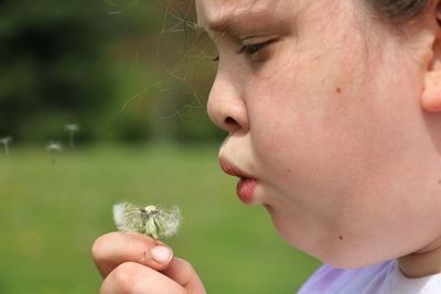 Side view of girl blowing dandelion