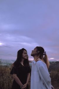 Young woman standing against sky during sunset