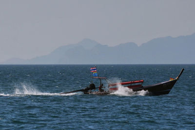 Fisherman sailing longtail boat at sea against sky