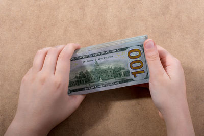 Midsection of person holding paper currency on table