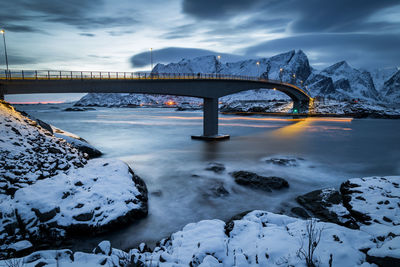 Bridge over snowcapped mountains against sky during winter