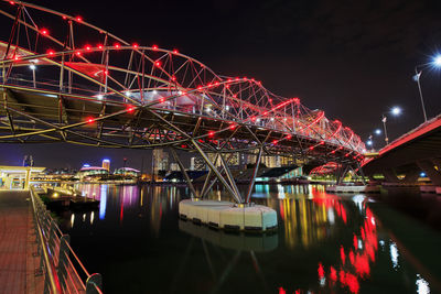 Illuminated ferris wheel by river against sky at night