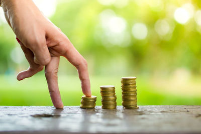 Close-up of human fingers climbing on stacked coins