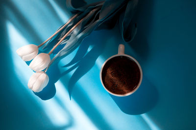 Directly above shot of flower with coffee cup on colored background