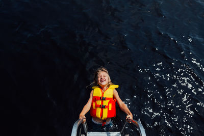 Young boy on dock ladder with huge smile