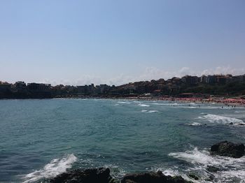 Scenic view of sea by buildings against clear sky