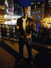 Full length portrait of young man standing in city at night