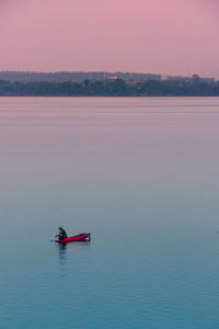 Man in canoe on lake against sky