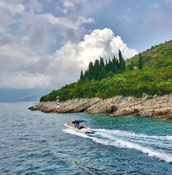 Scenic view of sea by mountain against sky