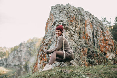 A young blonde girl walks in the autumn in the mountains with a view of the river and forest