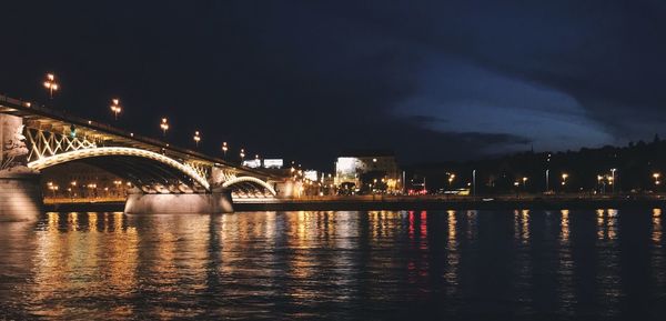 Illuminated bridge over river at night
