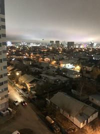 High angle view of illuminated street amidst buildings in city at night