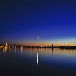 Scenic view of lake against clear blue sky at night