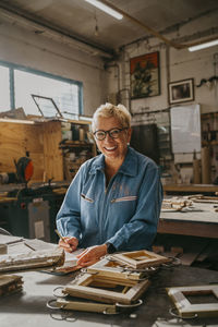 Portrait of happy senior female carpenter at repair shop