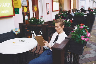 Young woman reading book sitting in cafe