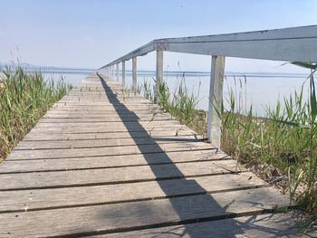 Footpath leading towards sea against sky