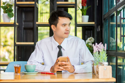 Young man using mobile phone while sitting on table