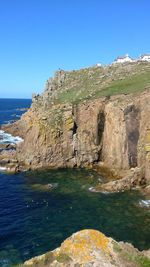 Rock formations by sea against clear blue sky