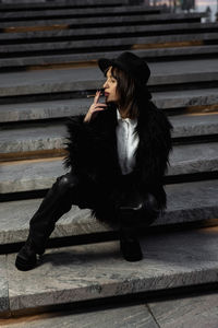 Side view of woman sitting on footpath