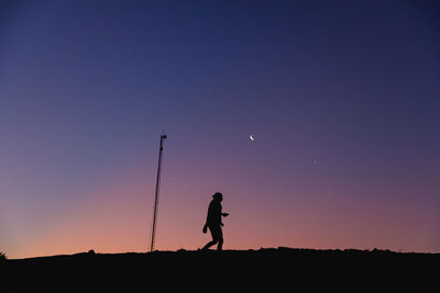 Silhouette man standing on field against sky at sunset