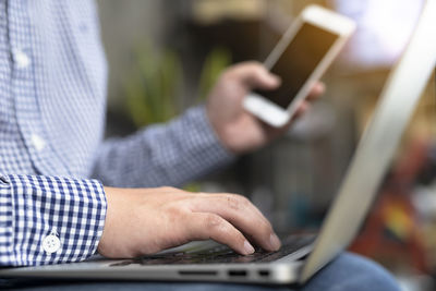 Midsection of man using mobile phone