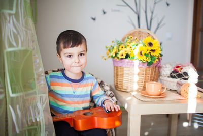 Portrait of boy sitting on table at home