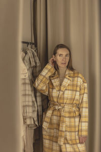 Woman trying on a coat in a fitting room of a clothing store