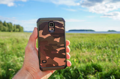 Close-up of hand holding camera on field