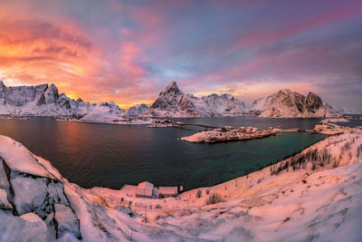 Scenic view of lake by snowcapped mountains against sky during sunset