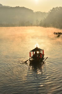 Boat in lake against sky during sunset