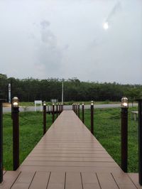 Footpath amidst field against sky