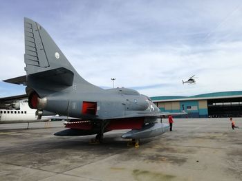 Airplane flying over airport runway against sky
